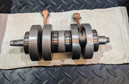 Crankshaft resting on a towel on a metal floor, showing multiple counterweights and bearing journals across its length