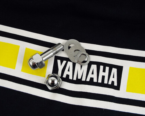 Assorted metal hardware—bolt, washer rings, and nuts—placed on a Yamaha banner.